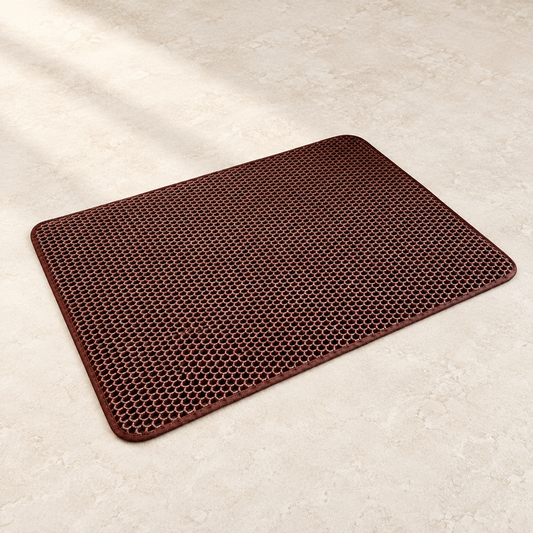 Brown rectangular honeycomb cat litter mat on a pale stone floor.